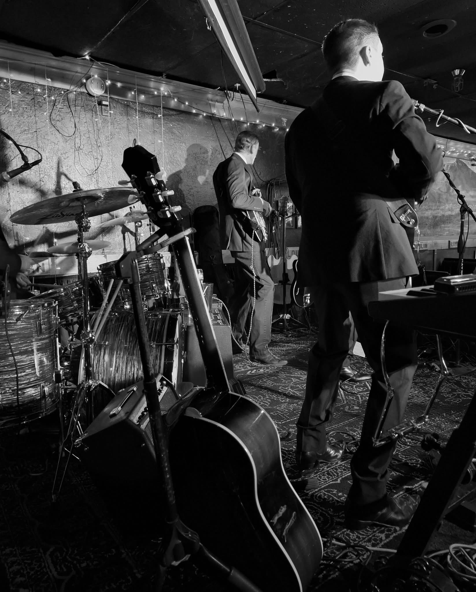 Boots & Suits on stage from behind, guitars at the ready